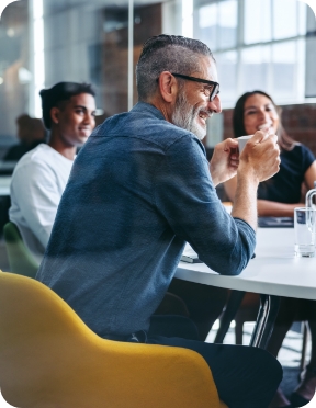 The businesspeople sit around a table, smiling.